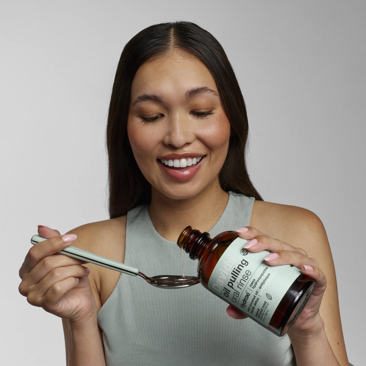 Modèle qui se sert une. cuillère à soupe de Bain de Bouche Oil Pulling + Nano-Hydroxyapatite - Davids.