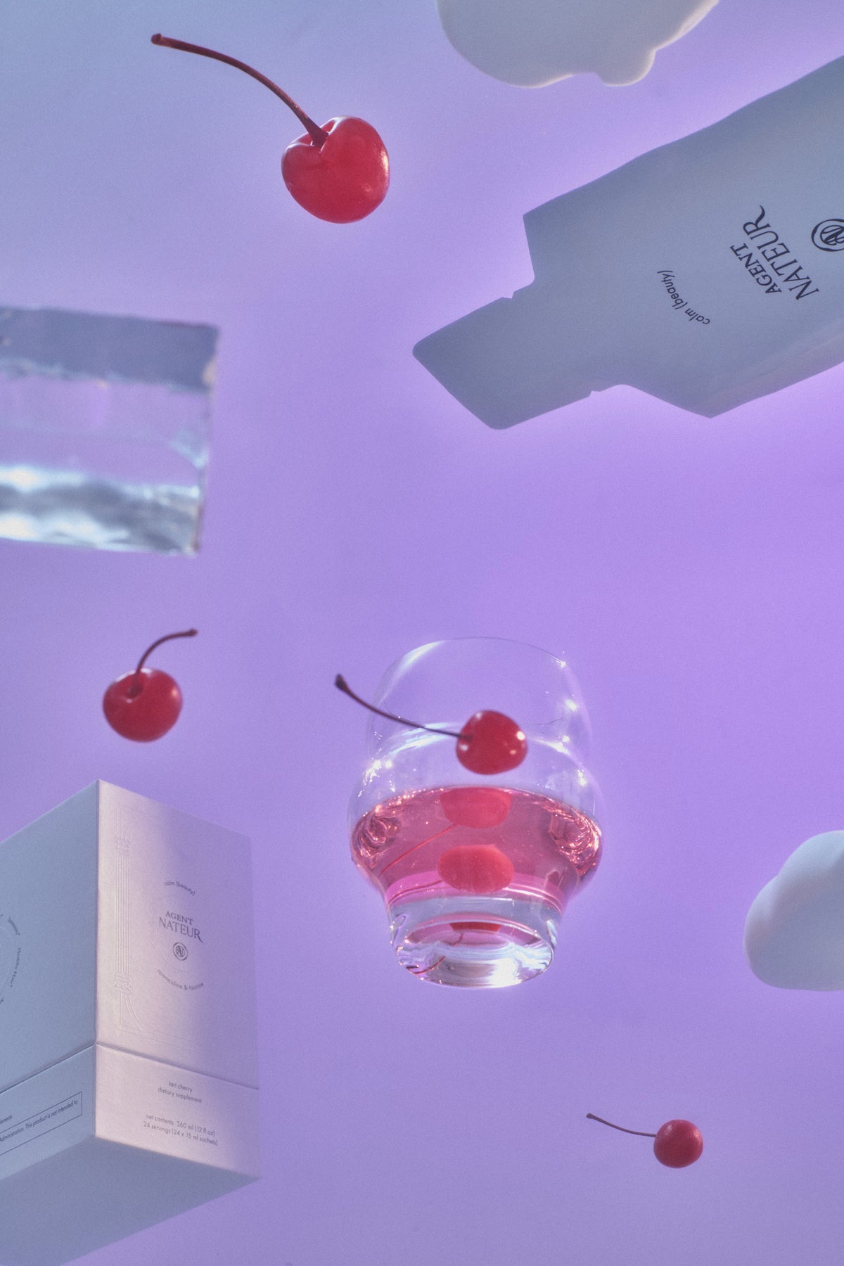 Calm (Beauty) - Agent Nateur - sachet, boîte et verre de boisson en apesanteur parmi des cerises