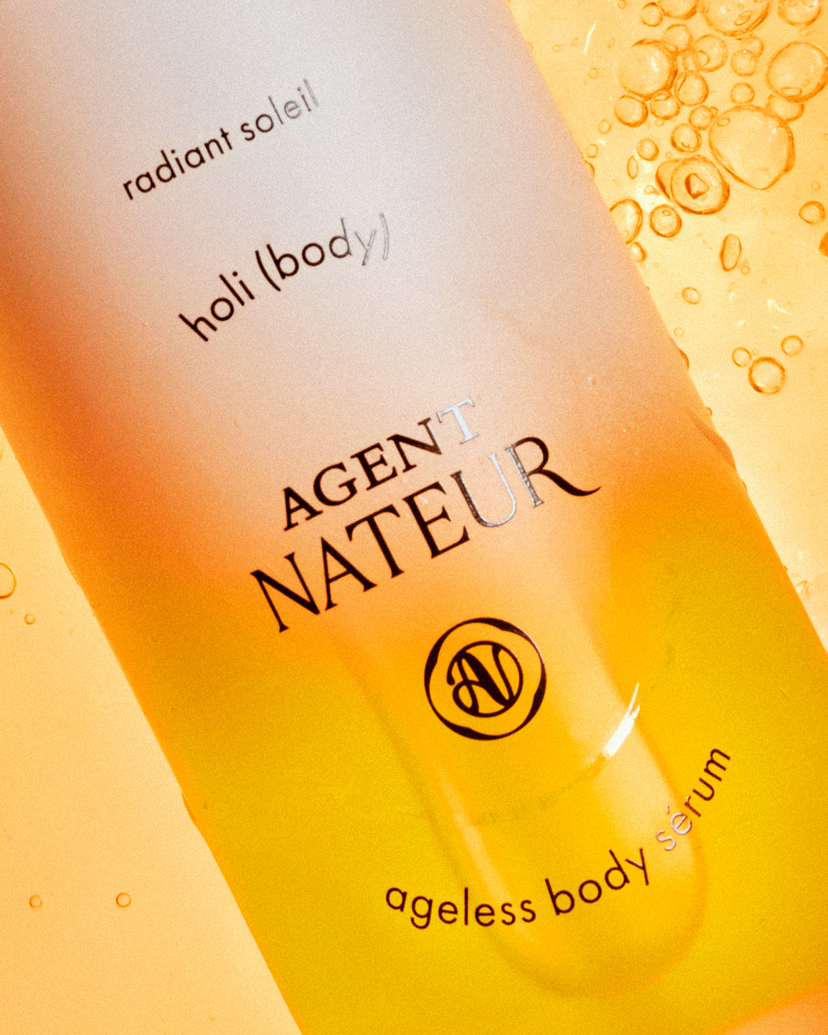 Holi (Oil) Body - Agent Nateur - gros plan du flacon sur fond de bulles dorées