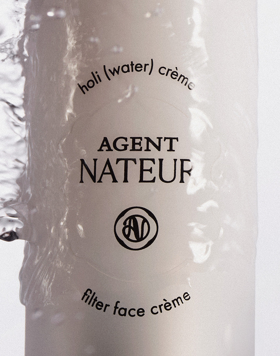 Holi (Water) Crème - Agent Nateur - gros plan du flacon sous une coulée d'eau